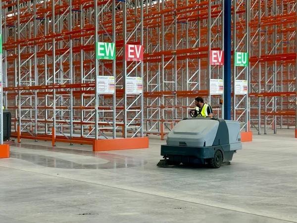Ride-on floor sweeper in a large warehouse facility